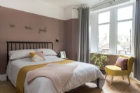 Modern guest room with dusky pink painted wall and yellow chair