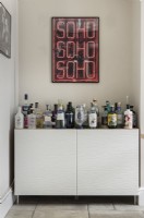 Drinks on sideboard with framed neon artwork on wall above