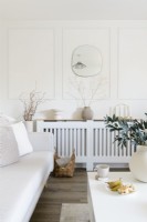 Modern white living room with wall panelling and slatted radiator cover