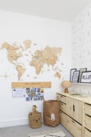Corner of a children's bedroom with pine storage units and a wall mounted wooden map of the world