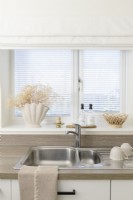 Stainless steel sink in front of window with venetian blinds