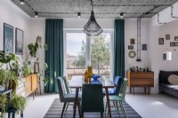 Retro dining room with large table, mix of chairs, plants and window in the background
