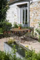 Rusting metal bistro table and chairs on terrace of country home