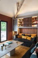 Cosy sofa covered with cushions within alcove of built-in wall unit