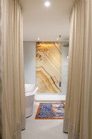 Marble feature wall in contemporary bathroom with golden curtains
