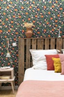 Detail of colourful wallpaper and recycled wooden pallet headboard