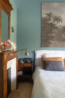Vintage painting on teal blue painted wall in country bedroom