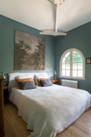 Arched window and teal blue painted walls in country bedroom