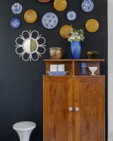 A collection of plates hanging on the wall above a retro recycled wardrobe