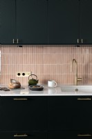 Pink splash back tiling and black units in modern kitchen