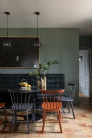 Black banquette seat against green wall in modern dining area