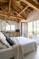 White country bedroom with vaulted ceiling and door to balcony