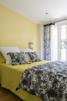 Bedroom with black and white patterned bedding and yellow walls 