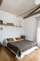 Country bedroom with white painted walls and wooden ceiling