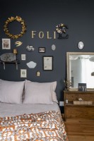 Display of small framed pictures on black bedroom wall