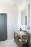 Wooden vanity unit in modern white bathroom with grey painted door