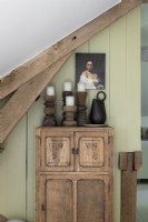 Carved wooden candlesticks on rustic cabinet with portrait painting