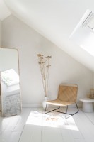 Wicker chair in white painted bedroom with long mirror