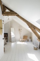 White painted bedroom in attic space with exposed wooden beams