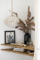 Vase of dried flowers and ornaments on corner shelf