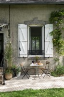 Small table and chairs outside window of country house
