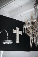 Silver cross ornament on black bathroom wall