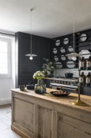 Distressed wooden island in modern country kitchen with black walls