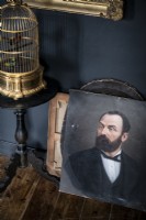 Classic portrait and gold birdcage against black painted wall