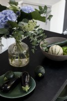 Flower arrangement and vegetables on black wooden kitchen island