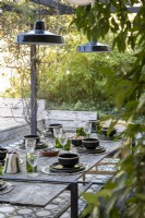 Outdoor dining table with pendant lights on pergola above