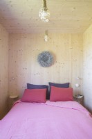 Small modern wooden bedroom with pink bedding