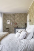Country bedroom with fireplace and floral wallpapered walls