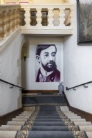 Large portrait of artist Toulouse Lautrec at bottom of classic staircase