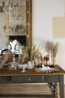 Display of dried grasses and flowers on sideboard next to mirror