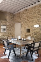Wooden table and chairs in country dining area with stone walls