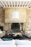 Large fireplace and exposed stone walls in country living room