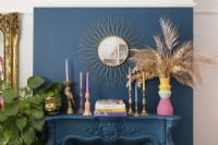 Blue painted chimney breast and mantlepiece with candlesticks and vintage mirror