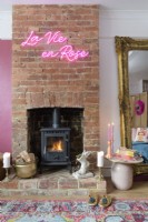 Neon sign on a brick chimney breast with a lit wood burning stove