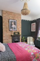 Exposed brick chimney breast in a green bedroom