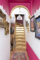 A gold painted staircase in a pink and white scalloped painted hallway