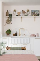 Ribbed butlers sink with scalloped shaped marble splash back and gold taps in a pale pink kitchen