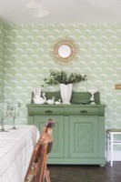 Upcycled green painted sideboard cabinet in front of green art deco inspired scalloped wallpaper