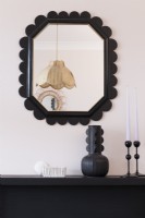 Black painted fireplace and art deco style upcycled mirror against a pale pink wall