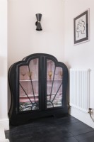Black painted glass fronted Art Deco cabinet in the corner of a dining room