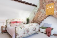 Brick double chimney breast in a bedroom with floral French upholstered double bed