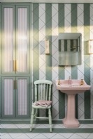 Green and white stripey tiled bathroom with pink basin
