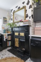 Old Victorian mantlepiece and range painted in black and gold in a monochrome kitchen
