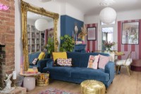 Large decorative guilt framed free standing mirror and blue sofa in a blue and pink living/dining room