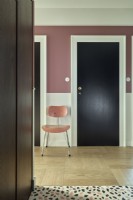 Chair in a modern pink hallway beside black wooden door