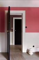 Two black doors and pink wall and wooden floor